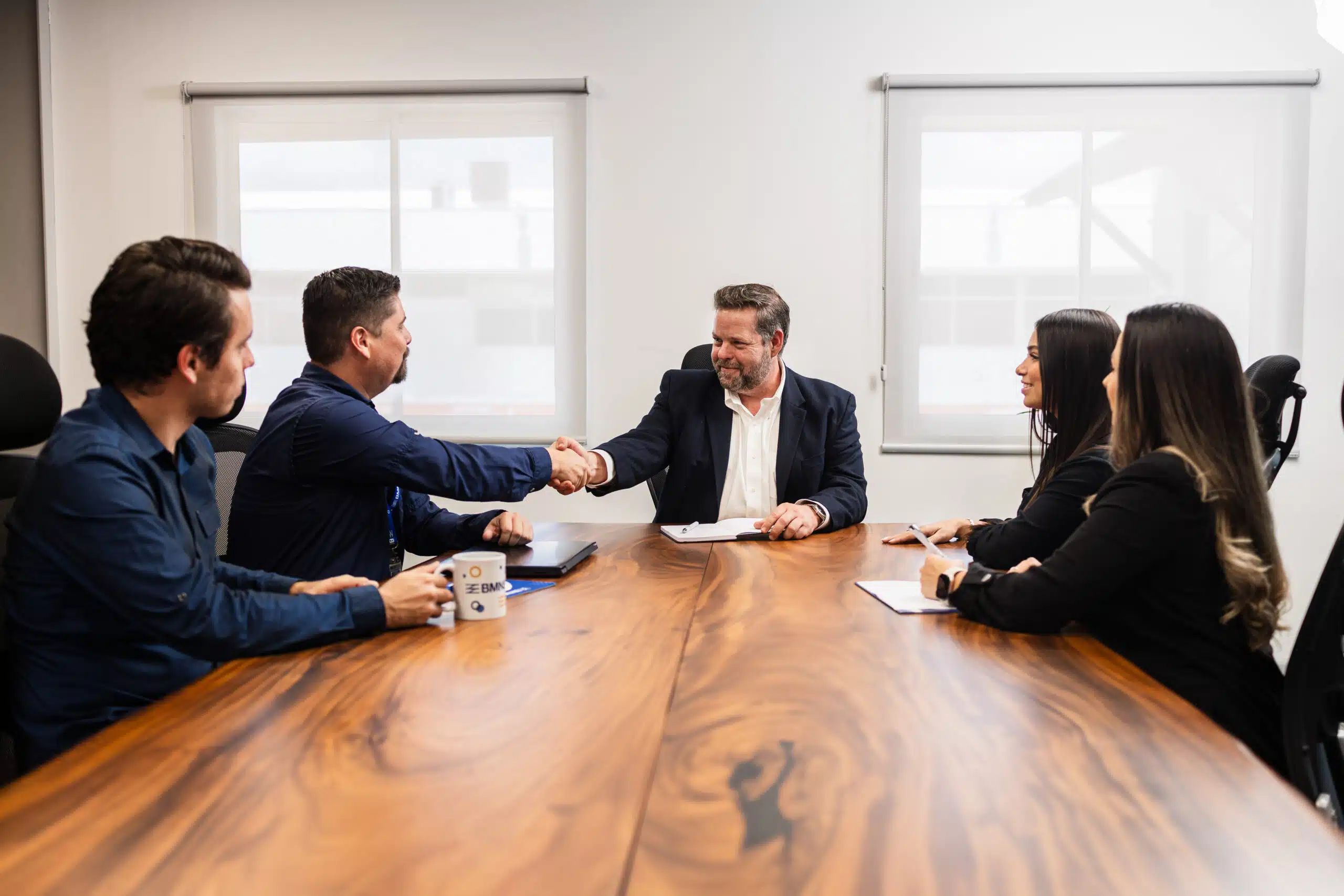 BMNS professionals sitting around a table and shaking hands
